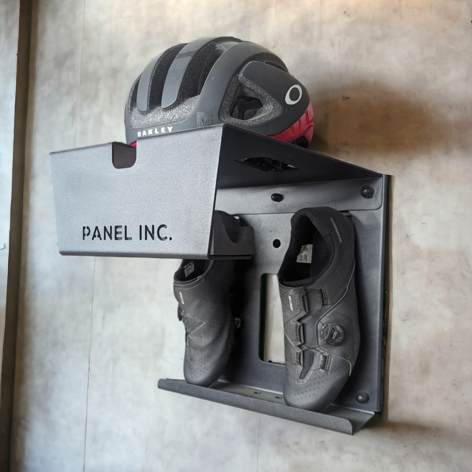 Wall-mounted bike helmet and shoe storage unit with 'Panel Inc.' branding.